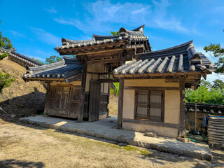 Fototapeta premium A small house with a wooden door and a wooden roof. The house is surrounded by trees and has a peaceful atmosphere
