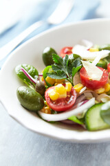 Simple Salad with Green Olives, Cucumber and Cherry Tomatoes. Bright wooden background.	