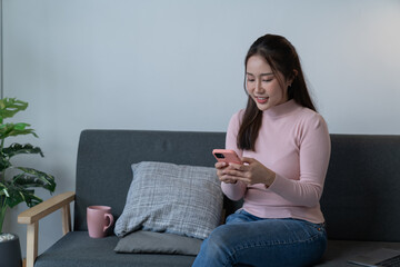 Fototapeta premium beautiful asian young businesswoman use mobile phone for chat with social media and laptop at home.Small Business Startup.
