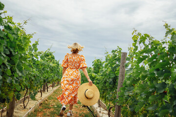 Joyful woman, wearing a hat, in a vineyard in the sun