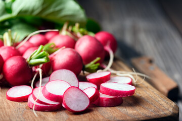 Slicing fresh farm organic pink radish on wooden board close up. Food photography