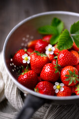 Fresh ripe red strawberry in metal colander on rustic wooden table. Food macro photography
