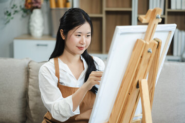Young female artist painting on canvas in the home studio, fine arts and creativity concept.
