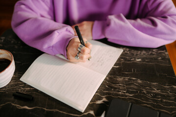 A woman writes in a notebook in a cafe