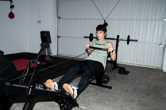 Woman Exercising on Rowing Machine in Home Gym