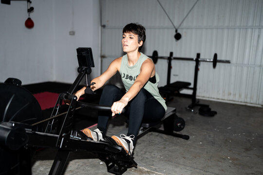 Woman Exercising on Rowing Machine in Home Gym
