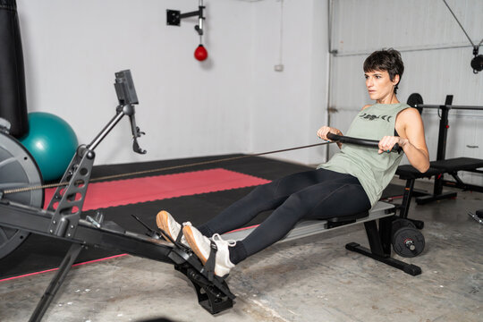 Woman Exercising on Rowing Machine in Home Gym