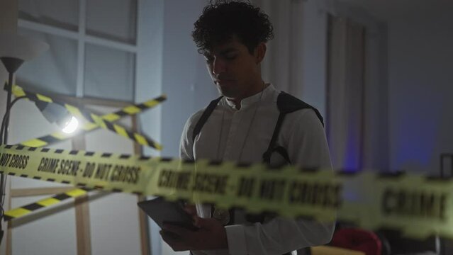 Hispanic man investigates a crime scene in a dimly lit indoor space with caution tape.