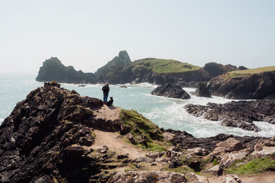 Walker and dog looking out to sea at Kynance Cove