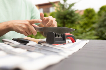 Close-up photo of man sharpening knives with special knife sharpener