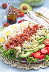 Cobb salad with greens, tomato, avocado, blue cheese, bacon, rotisserie chicken and eggs, vertical