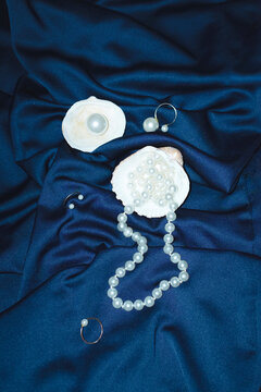 Ocean treasures: seashell and pearl on silk and hard direct flashlight