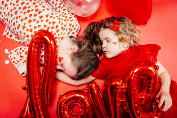 two kids laying down in studio surrounded with signs of love