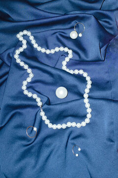 Classic white pearl jewellery on blue silk with hard direct flashlight