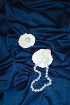Ocean treasures: seashell and pearl on silk and hard direct flashlight