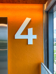 Floor level 4 in a parking ramp, garage, car parking with a large white number on an orange background.