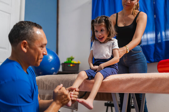 Smiling physiotherapist checking up on patient feet in clinic