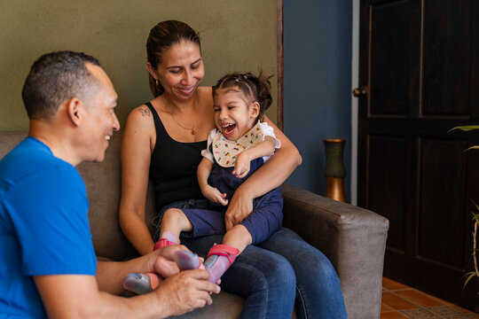 Physiotherapist helping happy disabled child wear leg braces at home