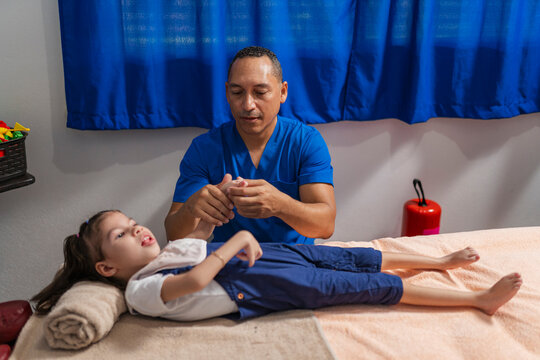 Focused osteopath examining fingers of child in hospital