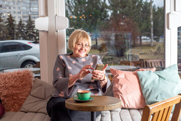 Woman 65+ uses a smartphone in a cafe