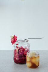 Glass jars with fermented cabbage, garlic  stand on a light stone background. On top of the jar lies a fork with cabbage and garlic