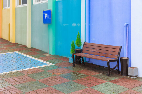Wooden bench next to multicolored building.