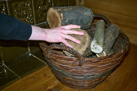 A young man takes a log to fire the stove