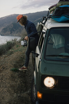 Stepping out of an old  campervan in Big Sur with a film camera