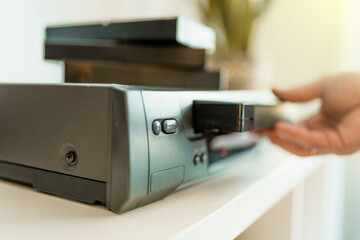 Close up of a hand holding a videotape. Retro vhs cassete in a player.