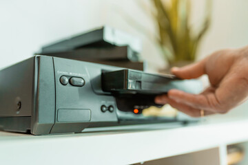Close up of a hand holding a videotape. Retro vhs cassete in a player.