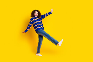 Full length photo of ovejoyed funny girl wear knit pullover jeans danicing on one leg have fun isolated on yellow color background