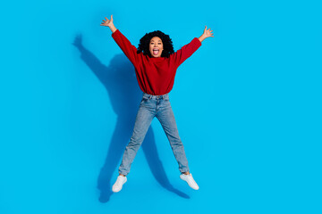 Obraz premium Full body photo of attractive young woman jump stretch legs hands dressed stylish red clothes isolated on blue color background