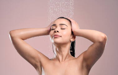 Shower, hair and skincare with woman in studio for cleaning, relax and morning routine for wellness. Water, washing and girl with healthy skin, fresh beauty care and body grooming on pink background