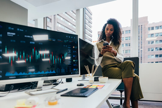 Professional black woman using smartphone in modern office