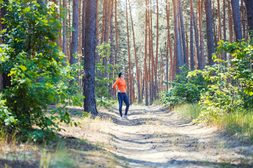 Obraz premium young girl on a morning run in a sunny pine forest
