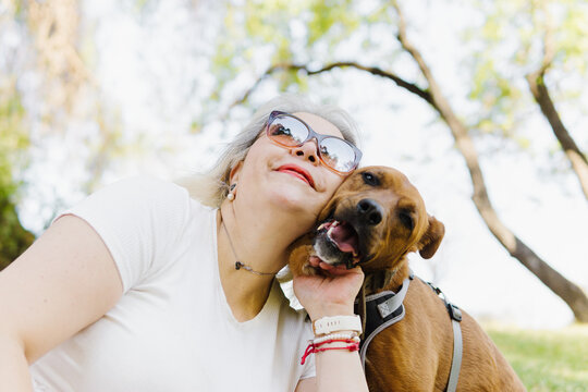 Portrait of a woman hugging a brown dog.