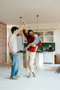 Happy couple and son dancing in kitchen