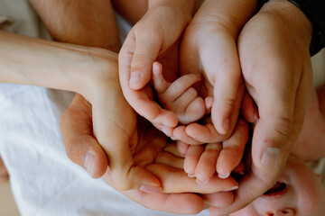 dad's and mom's hands hold the baby's hand