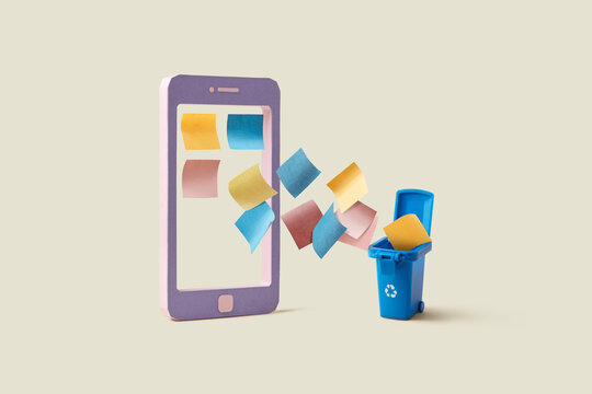 Sheets of paper falling from cellular phone into blue trash bin