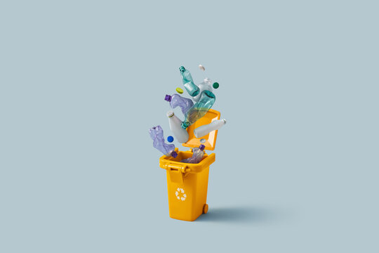 Used plastic items popping out of full yellow recycling bin in studio