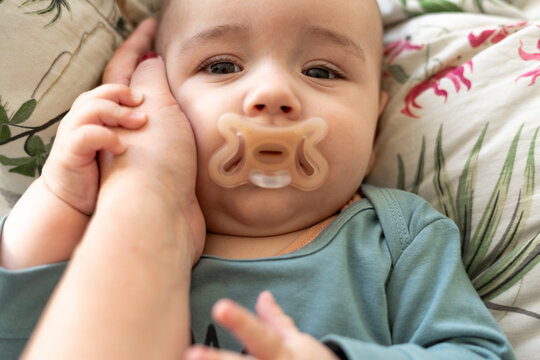  baby resting on a bed, being gently held by mother