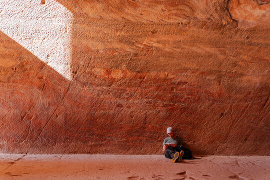Traveler reading a book in Sandstone cave, Petra, Jordan