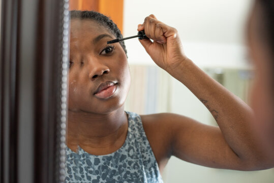 Girl in the mirror applying mascara