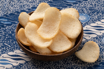 Bowl with fresh baked Indonesian shrimp krupuk close up on a batik cloth