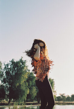 A woman twirling in the nature in a whimsical outfit by the lake