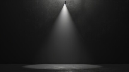 A minimalist black paper background with a single spotlight illuminating a product in the center.