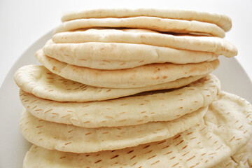 Pile of naan bread on a plate. 