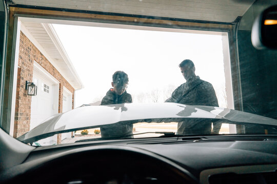 Father and teen son working on car together. 