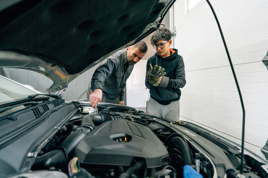 Father teaching son car maintenance.