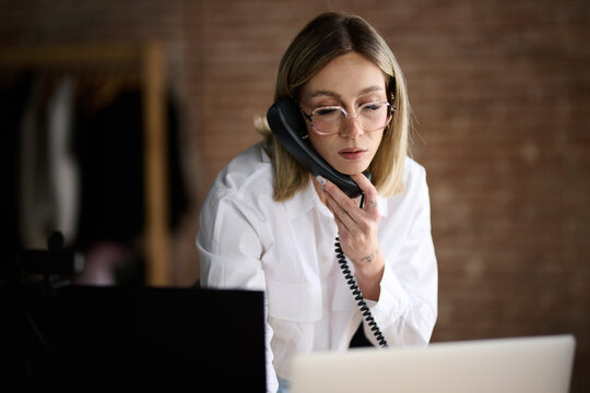 Dedicated Businesswoman Multitasking with Phone and Laptop